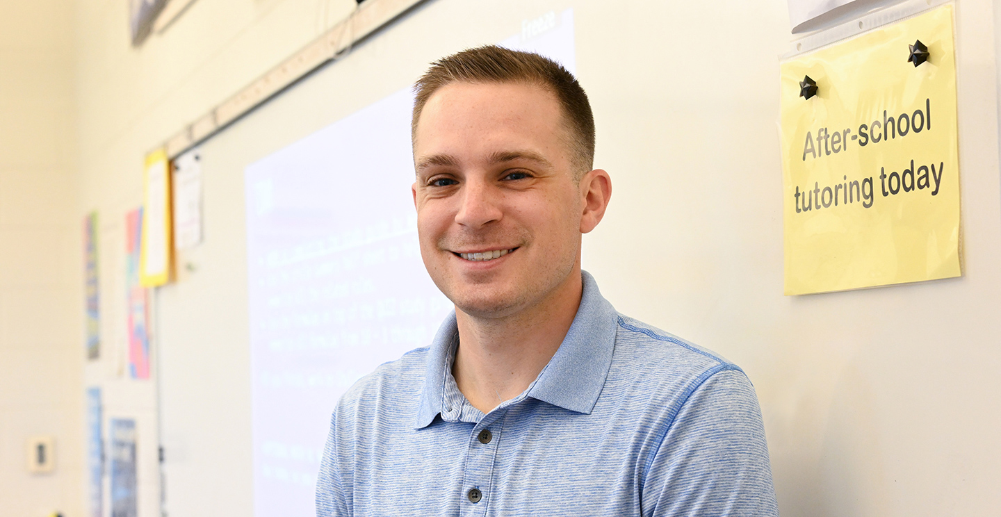Male teacher standing by a dry erase board.